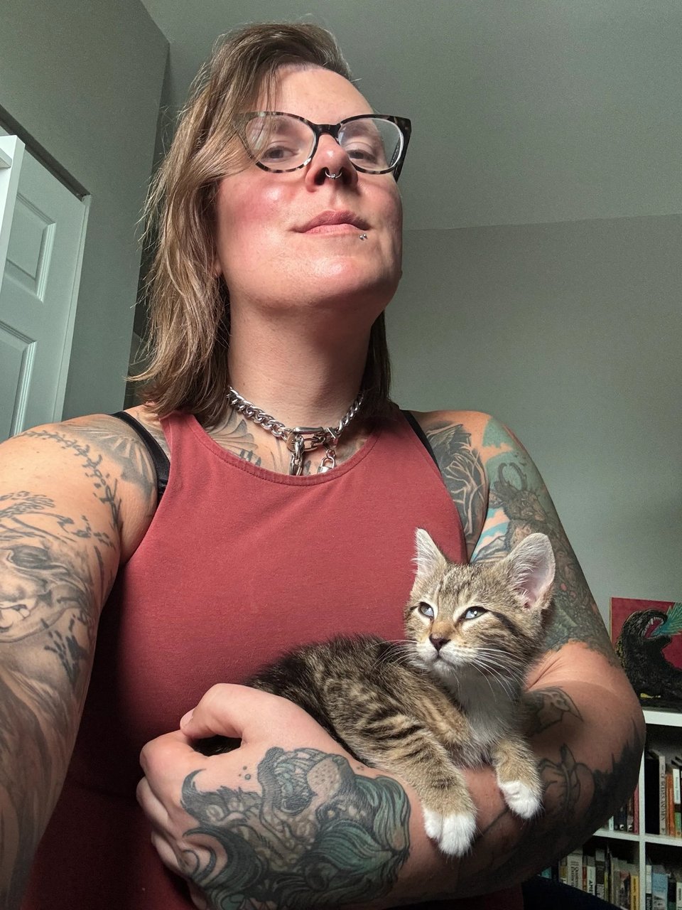 Selfie of Riley and Kazoo the kitten, who is very sleepy in Riley's arms (hence her nictitating membranes being visible).