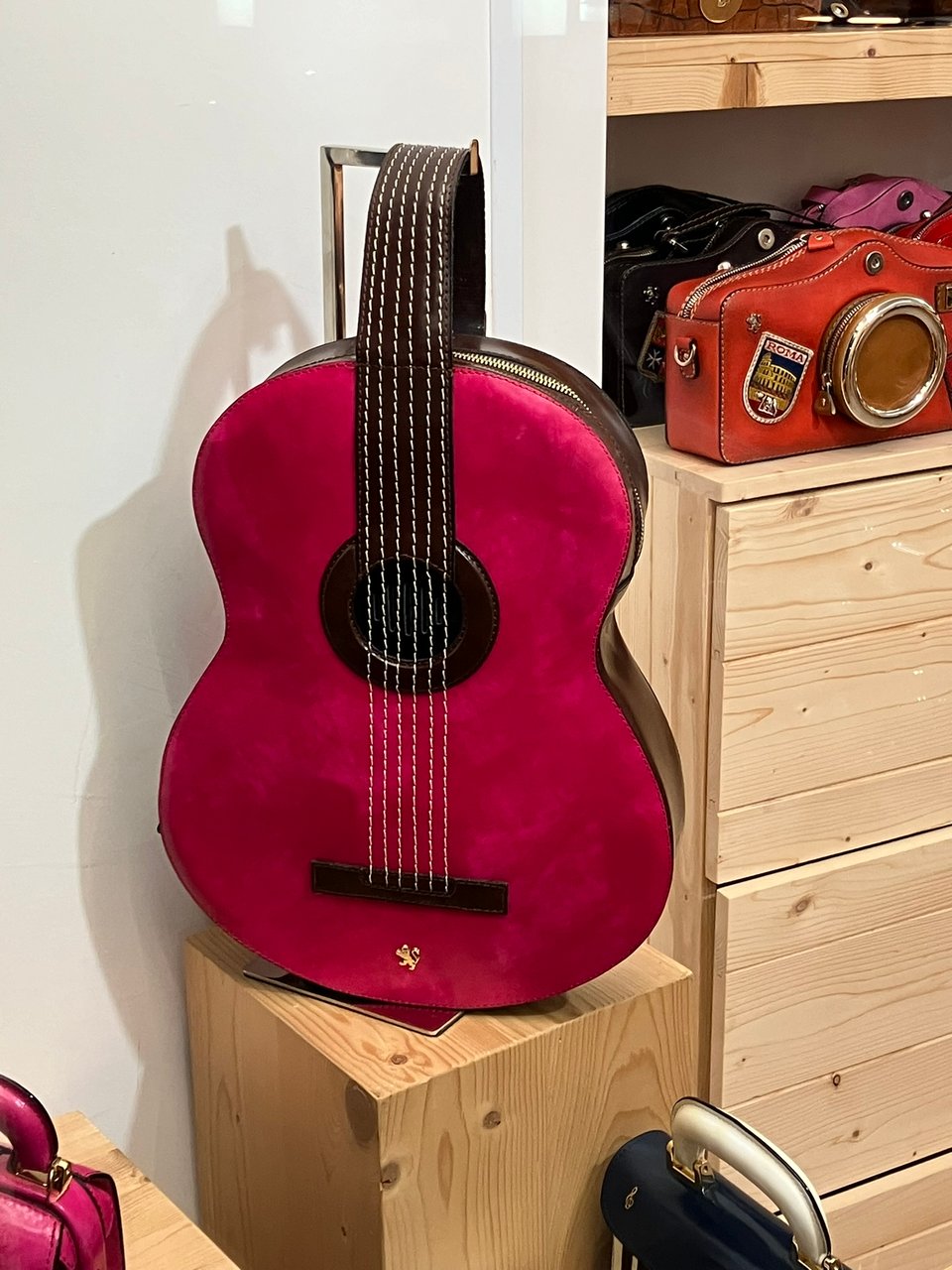 A handbag in a Roman store window. It's shaped like a guitar and it's a very distinctive hot pink.