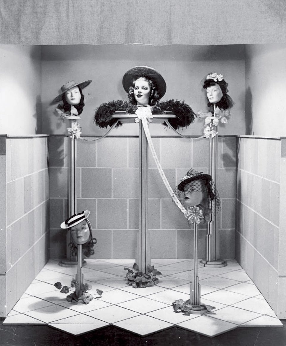 Photo of what appears to be a woman's head floating in a shop window, with four mannequin heads around her