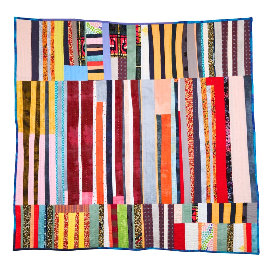 Photo of a patchwork quilt by Sarah Atlee. The quilt is composed of three sections of mostly vertical stripes in all colors.