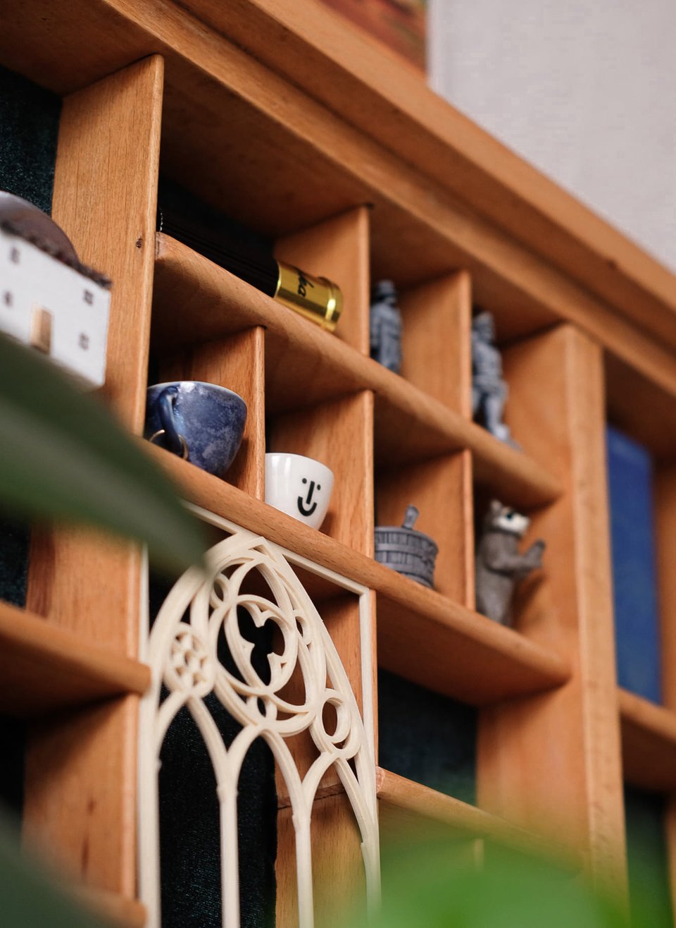 Photo close-up of the compartments and the trinkets inside. Two miniature teacups and grey RPG figurines, as well as a 3D-printed gothic window frame.