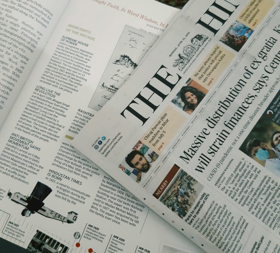 A newspaper and a magazine, laid flat on a surface.  Photo by Ashni on Unsplash