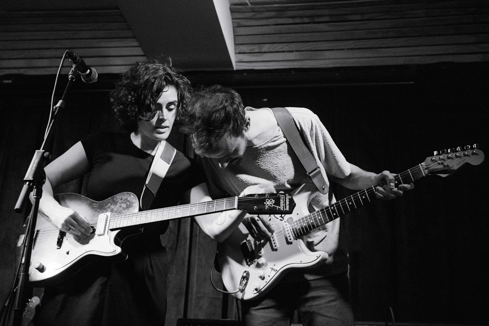 black and white photo of 2 musicians whispering to each other on stage