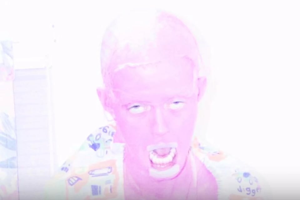 A pink humanoid creature with dead-looking eyes and an open mouth. It is bald and wearing a sheet over its shoulders.