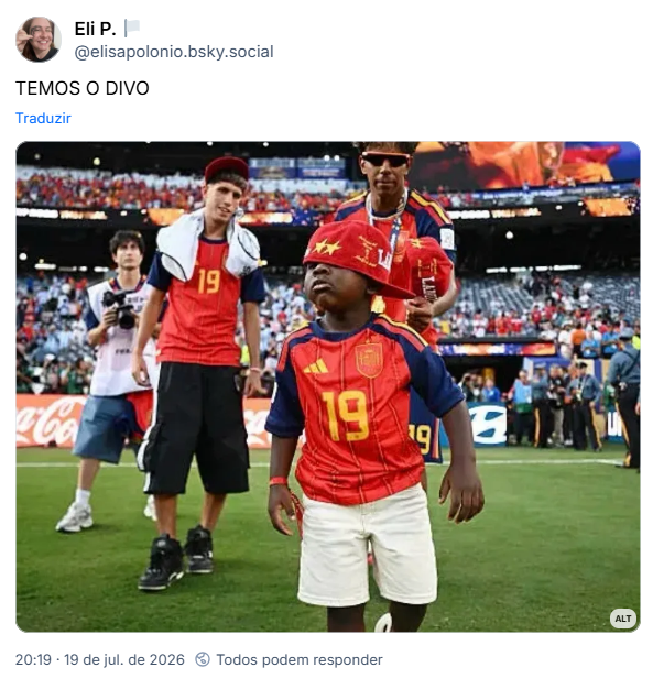 Post de Eli P. 🏳️ (@elisapolonio.bsky.social): TEMOS O DIVO
Post ontém imagem com a seguinte descrição: O irmãozinho de Lamine Yamal, Keyne Yamal, domina completamente a cena da festa da Espanha. Na foto, ele está em primeiro plano usando a camisa 19 do irmão e um boné vermelho de aba reta tão baixo que cobre os olhos inteiros, andando cheio de marra, como o protagonista da festa que ele é. Ao fundo, alguns metros atrás, Lamine Yamal observa a cena com óculos escuros.