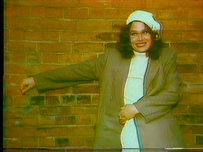a woman leaning against a brick wall
