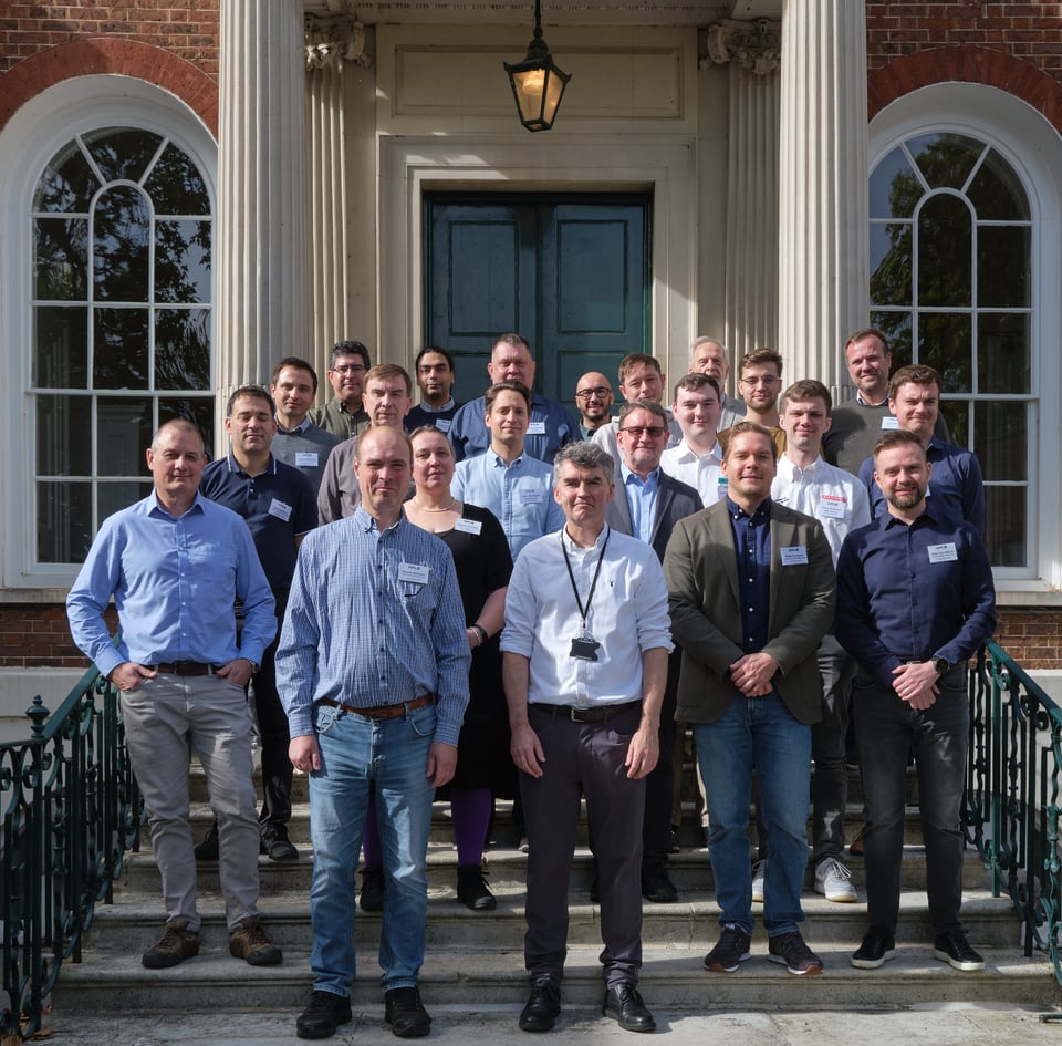 A group of temperature measurement experts stand in the sunshine outside Bushy House in London