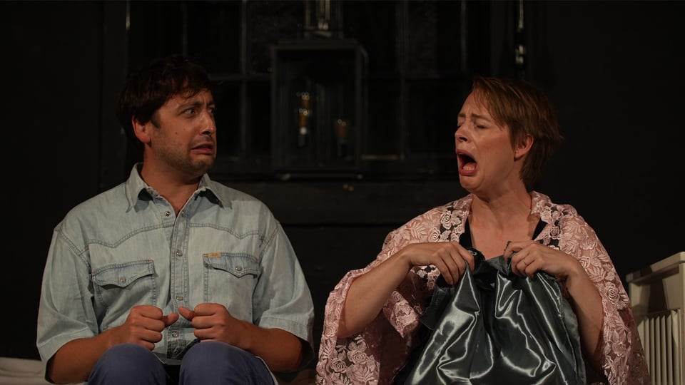 Picture of Laura and Gael making funny faces, sitting on a bed during a performance.