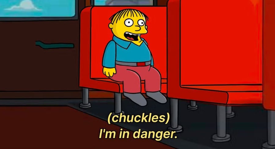 A screenshot from The Simpsons of Ralph Wiggum sitting on the school bus. The text reads: (chuckles) I'm in danger.