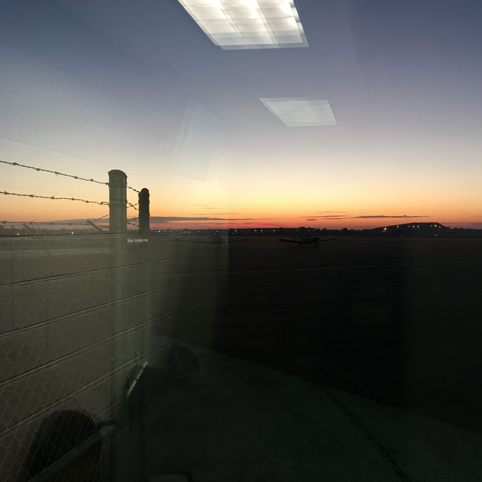 Window reflection of fluorescent lights against the dawn rising over the Macon airport.