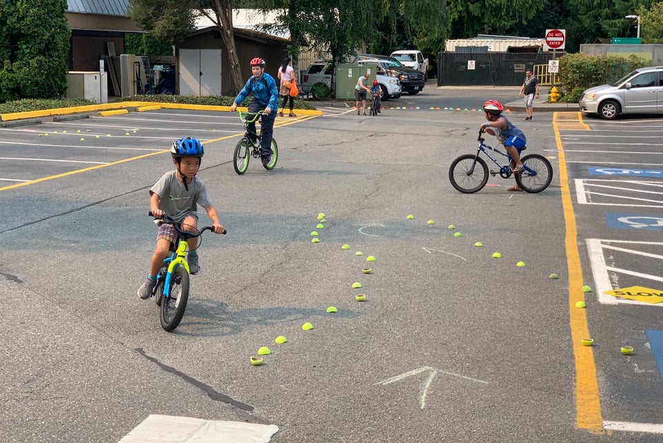 a group of children riding bikes in a parking lot