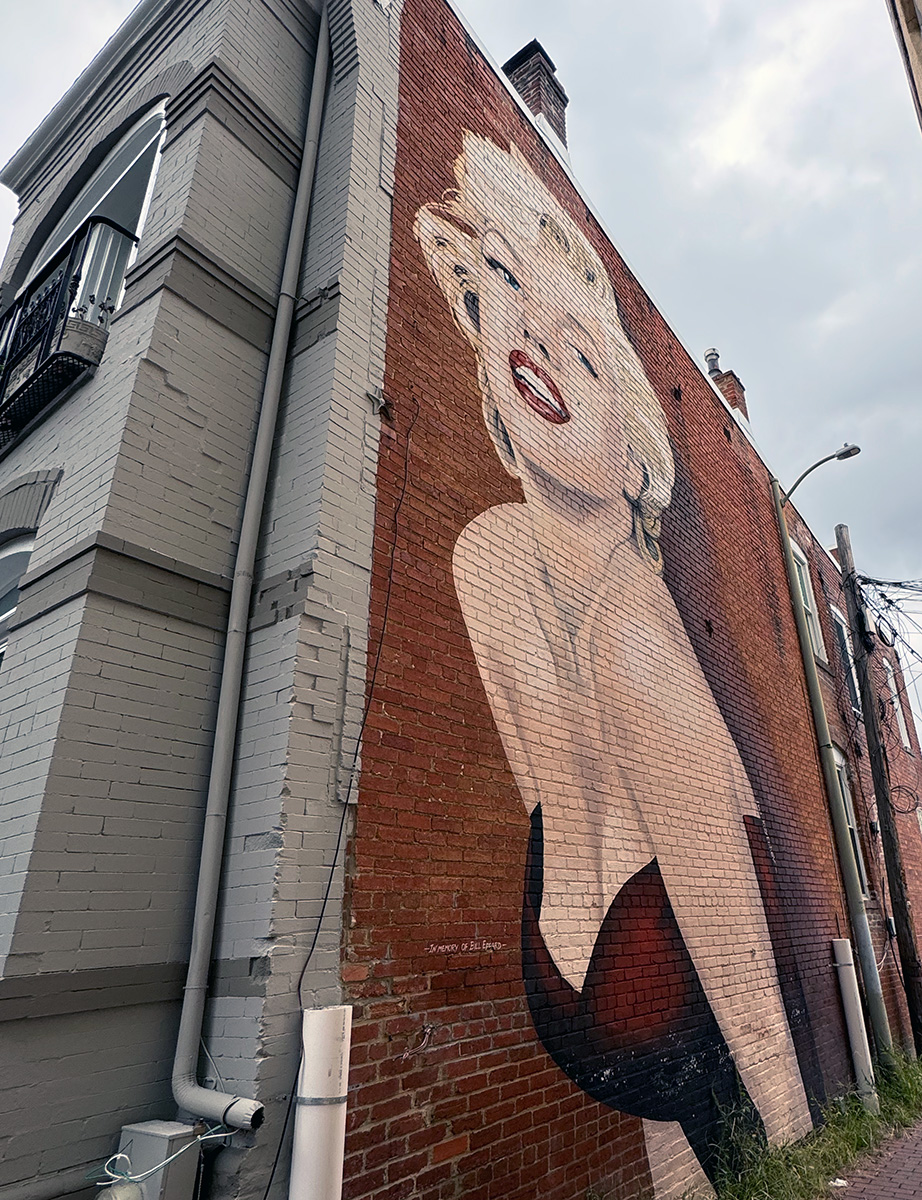 A mural of Marilyn Monroe on the side of a brick row house.