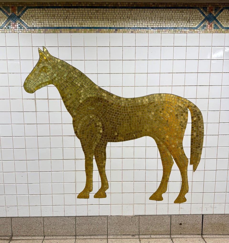gold-colored tile mosaic of a horse in profile on a white tile wall