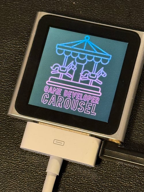 An iPod Nano plugged in, displaying the Game Developer Carousel logo on the screen.