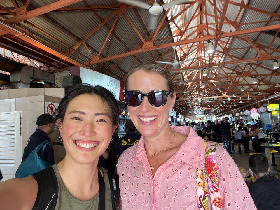 A selfie with Annabel, who has blonde hair, a pink dress, and sunnies, in a hawker centre