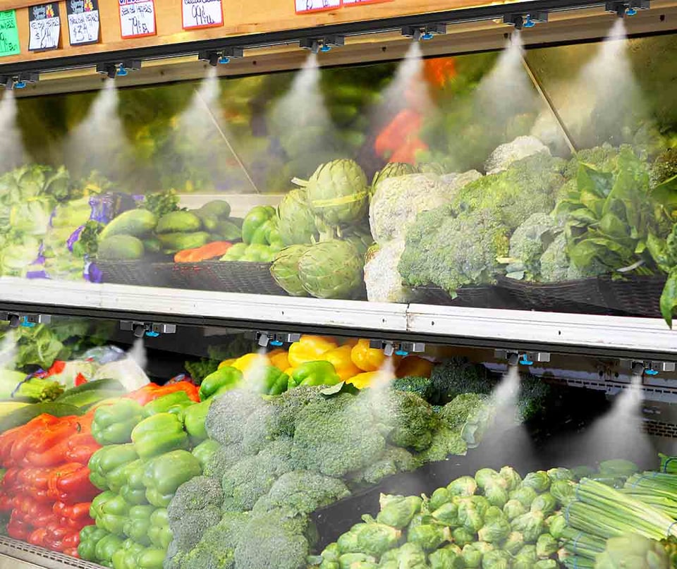supermarket vegetables being misted by produce sprayers built into the chiller shelves