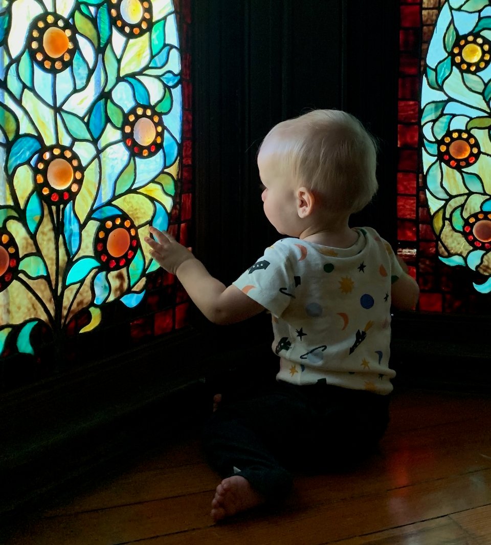 A young toddler sits and examines a stained glass window