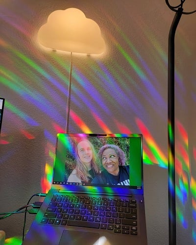 my open laptop with wallpaper of me and my wife. An IKEA cloud lamp is on the wall. Rainbows are everywhere.