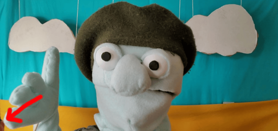 A still from the Sock Puppets Kickstarter video. Herman looks at the viewer. In the very bottom-left of the screen, Kurt's ear can be seen.