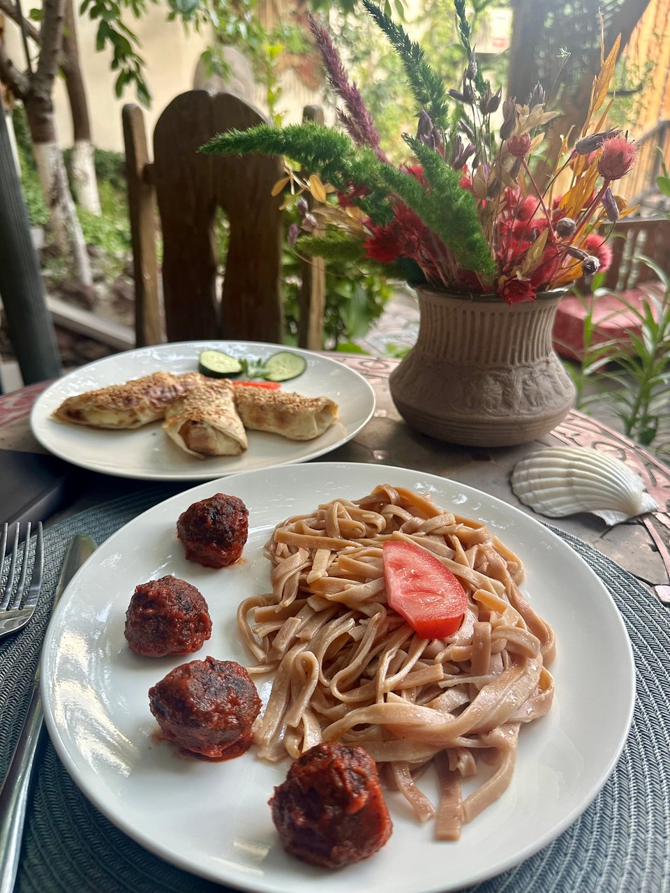 a plate of beef meatballs and noodles and a plate of lavash-wrapped cheese