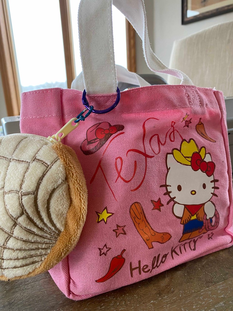 a small pink Hello Kitty Texas themed canvas tote and a zipper plush pouch in the shape of a concha