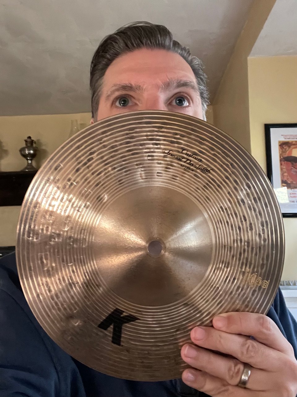 A man's eyes peek above a 10 inch splash cymbal