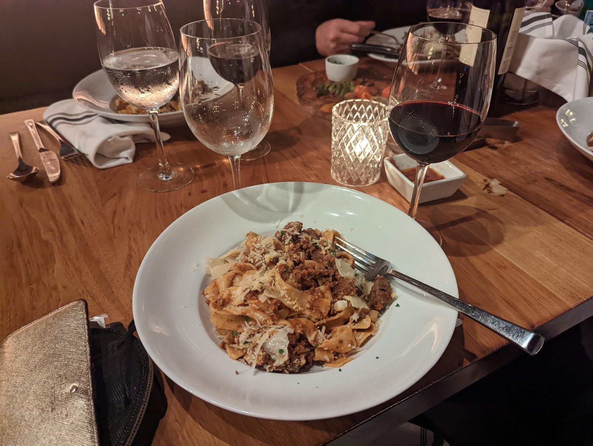 My bowl of pasta from Atalian. Appetizers and wine glasses are visible on the table