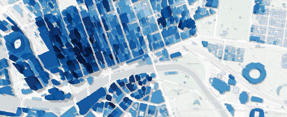 a 3d rendering of buildings centred on Flinders Street station in Naarm/Melbourne, Australia. Taller buildings are dark blue, while shorter buildings, and surroundings, and a paler blue. The Yarra River is a grey snake through the cityscape, and the MCG is rendered as a weird blue donut to the east of the CBD.