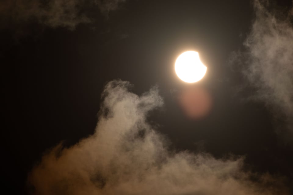 Partial lunar eclipse of the sun with a small bite out of the top right of the sun
