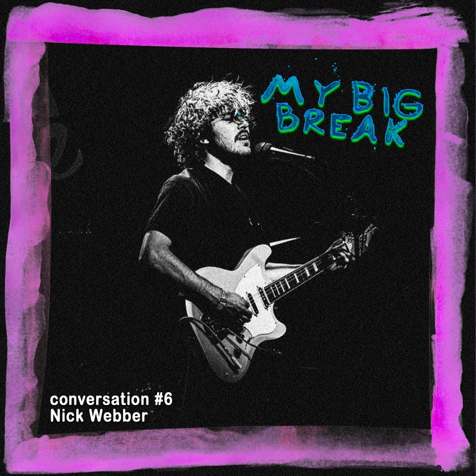 the musician Nick Webber sings into a microphone with a cool looking guitar