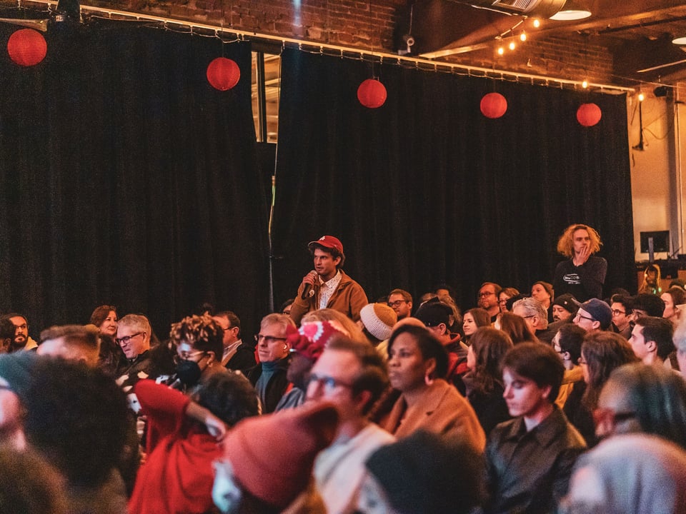 Image of man in red baseball cap standing with microphone at Motorco