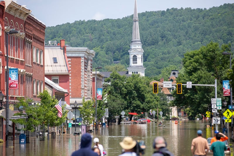 a view looking down montplier vermont's main street, entirely flooded with several feet of mostly still water