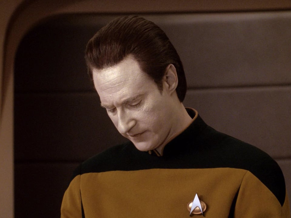Data is looking down at his computer console. His brow is furrowed and his lips are pursed in concentration and perhaps frustration.
