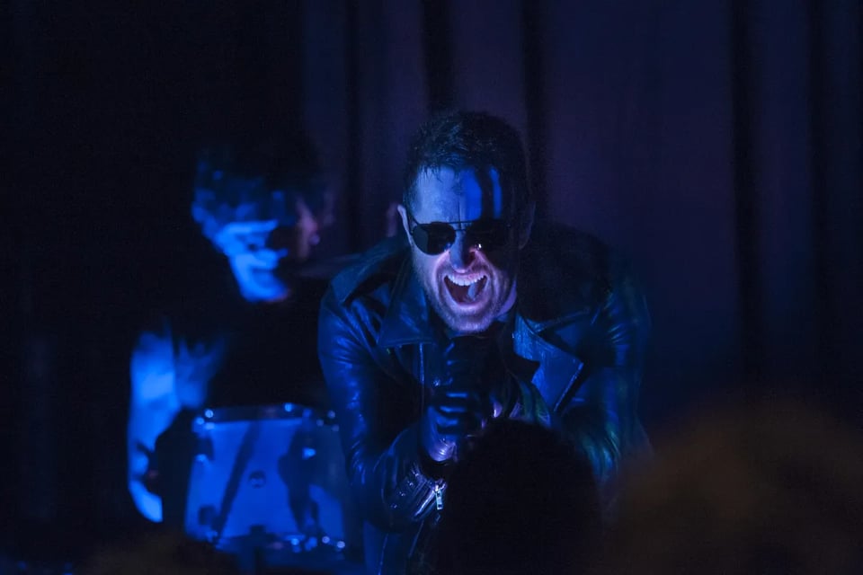 Trent Reznor screaming into a microphone with blue and purple lighting abounding.