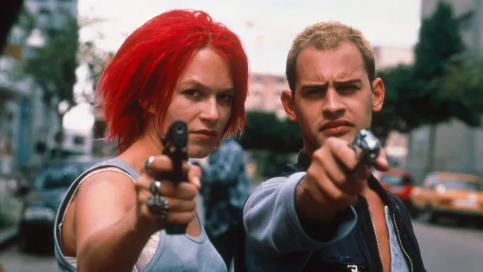 A shot from Run Lola Run, the 2 main characters are pointing guns at the camera
