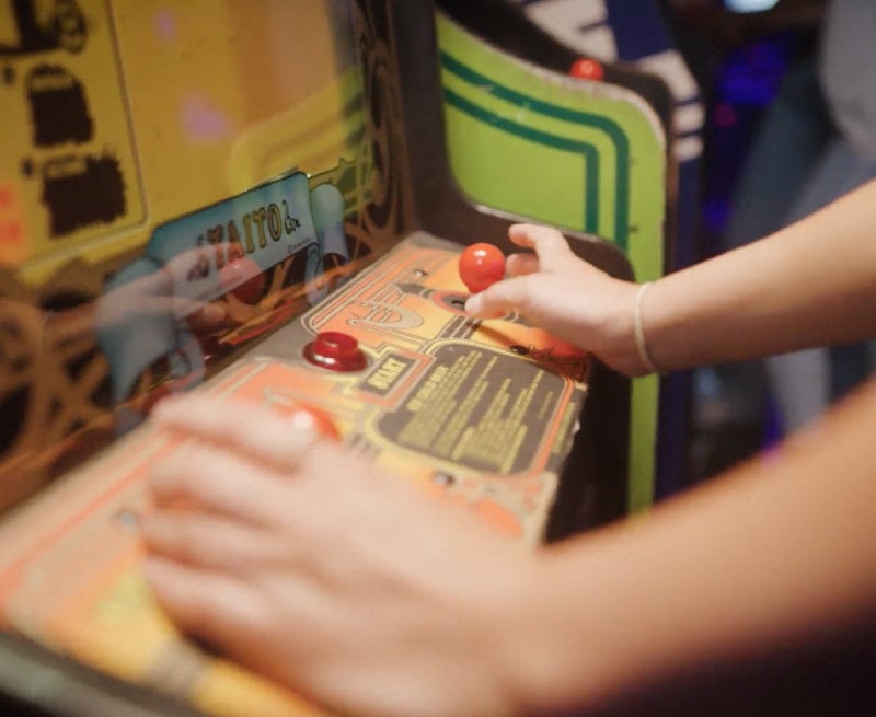 A player using the joysticks on the arcade game Ice Cold Beer.