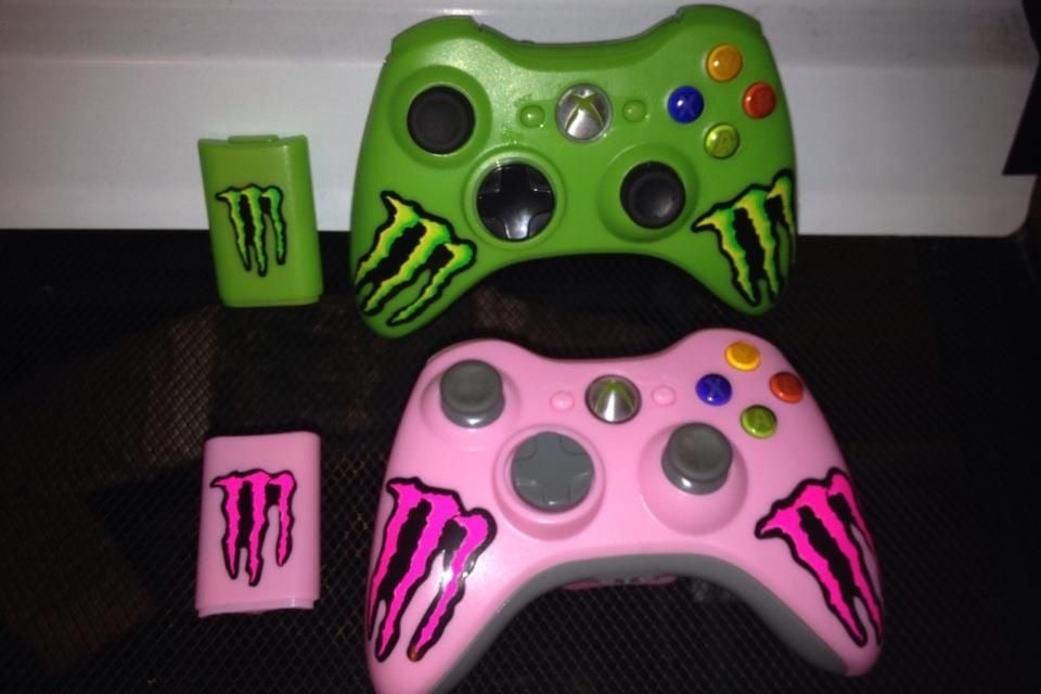 two monster energy-branded xbox controllers. one is pink and the other is green
