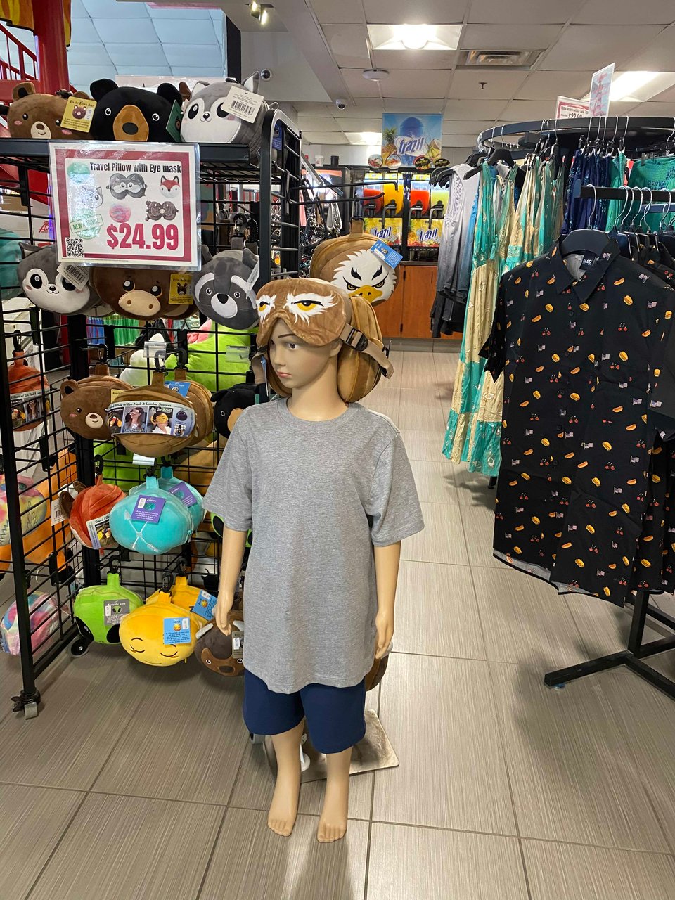 a small boy mannequin in a large tshirt and shorts with a fuzzy headgear travel pillow and eye mask combo