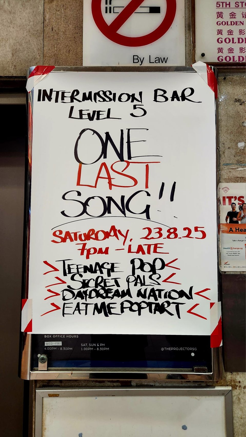 A handwritten sign. On the first line, it reads: INTERMISSION BAR LEVEL 5. On the next three lines, it reads: ONE LAST SONG!! The next line reads: SATURDAY, 23.8.25. After that, it reads: 7pm - LATE. And the last four lines read: >TEENAGE POP< >SECRET PALS< >DAYDREAM NATION< >EATMEPOPTART<