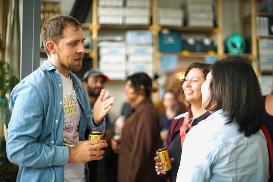A group of people talking, beers in hand