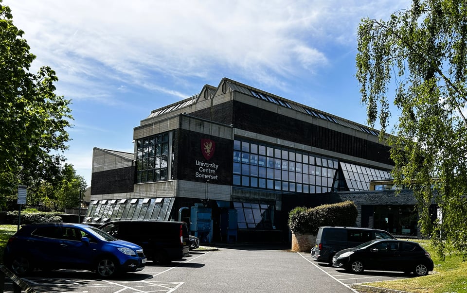 A large building made up of one large block and several smaller ones. The long wall of the main block has two floors entirely made up of glass, creating floor to ceiling northern light. The transverse glazing in the roof is visible.