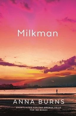 A person walks along the shore line under a red, pink sky. The front page of a book, Milkman by Anna burns.
