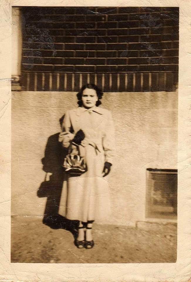 Photo of Ana from the 1950s(?) standing in front of a building in New York.