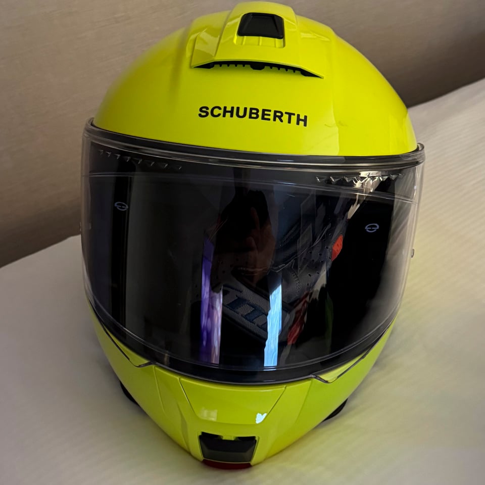 A bright yellow motorcycle helmet, on a hotel bed.