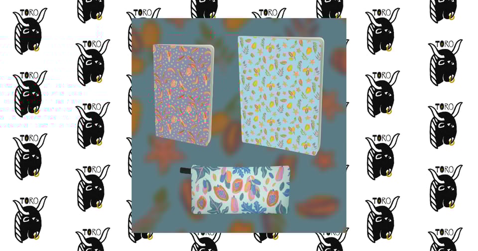 a small muted blue notebook with a repeating yellow and red banana illustration, a large light blue notebook with a repeating yellow, purple and pink star fruit illustration, and a light turquoise pencil case with a pink, orange, green, and blue papaya illustration, on a blurred background. Image is set atop a repeating pattern of the TORO logo.