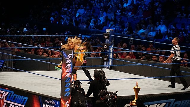 A screenshot of a WWE smackdown match between two women, while a ref looks on