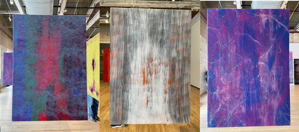 Three felt artworks, one blue and red, one gray black and orange, another violet and pink