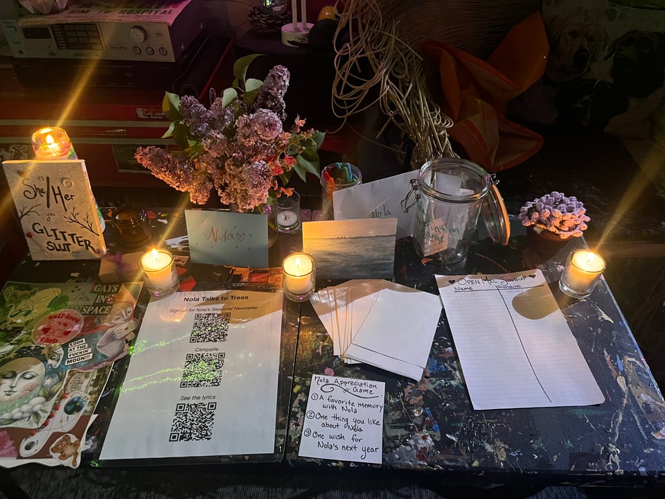 a birthday table with candles, lilacs, music paraphernalia, and friend art
