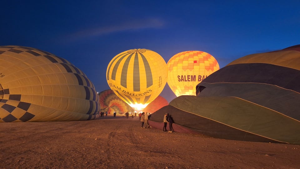 Five balloons in various stages of lift-off. Flames are visible to two of them.