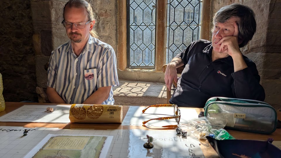 Two RPG gamers ponder the wonders of RuneQuest, as light shines on to the table in the Earl's Chamber of Chepstow Castle